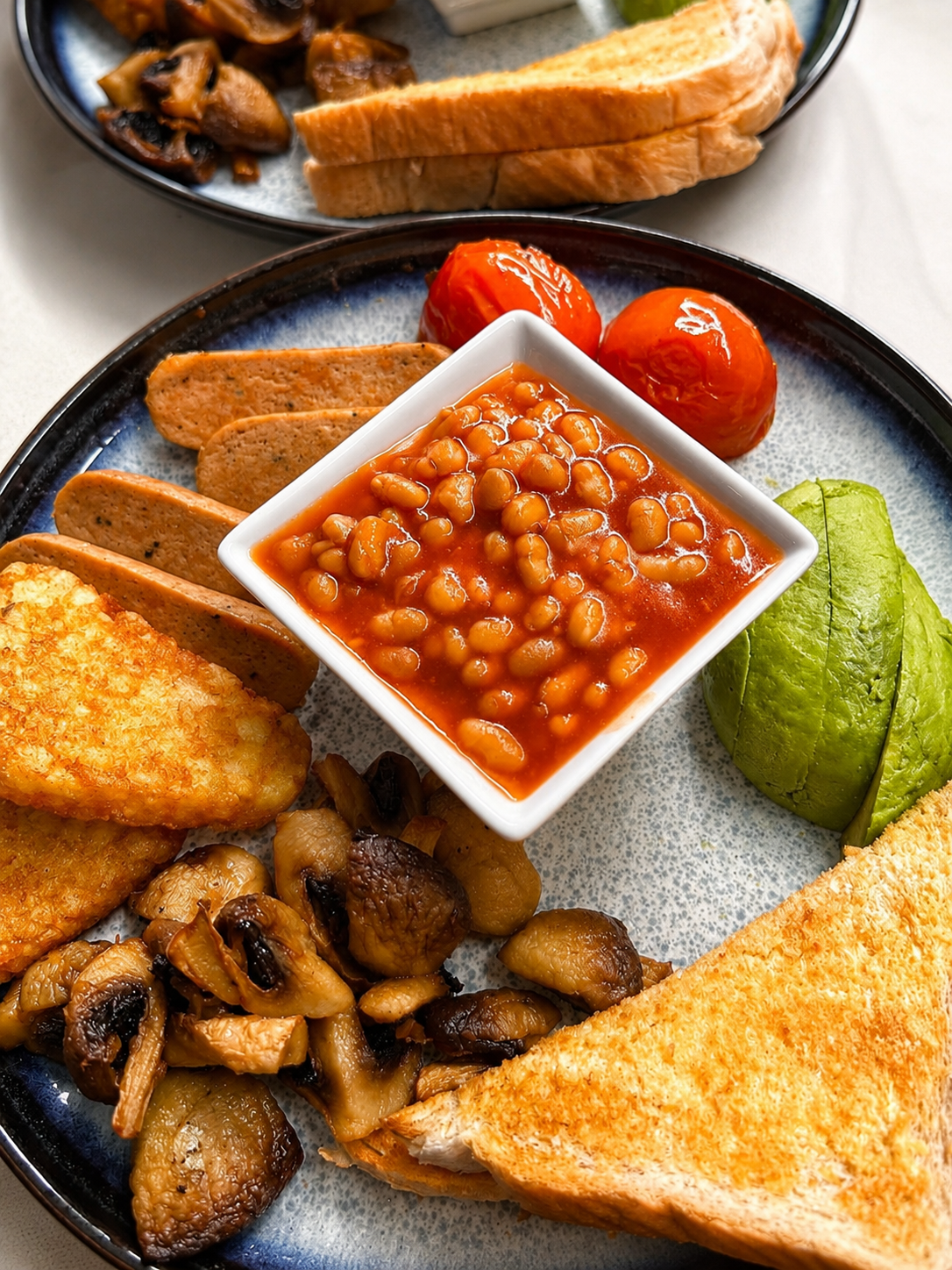 A full breakfast with beans, avocado, mushrooms, hash browns and toast