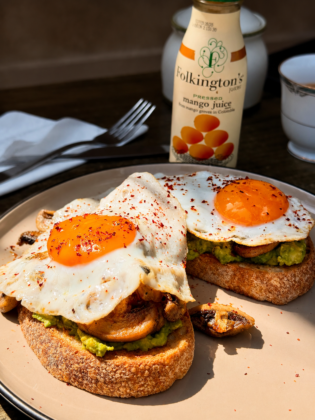 Avocado toast topped with fried eggs and mushrooms
