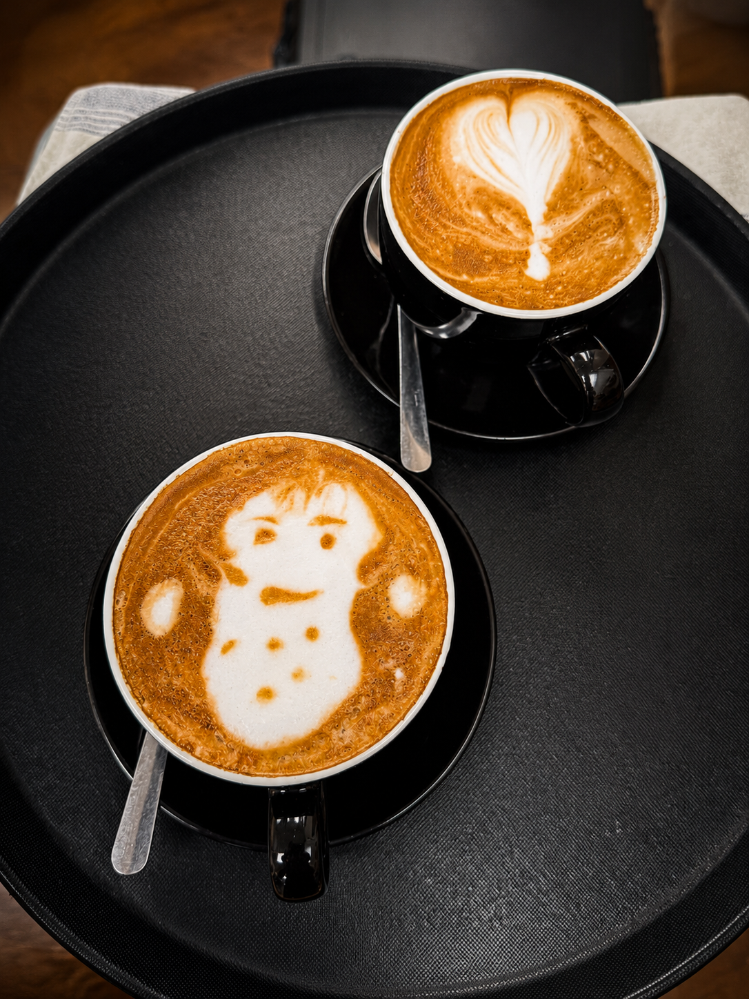 Two coffees with latte art served at The Nook Cafe